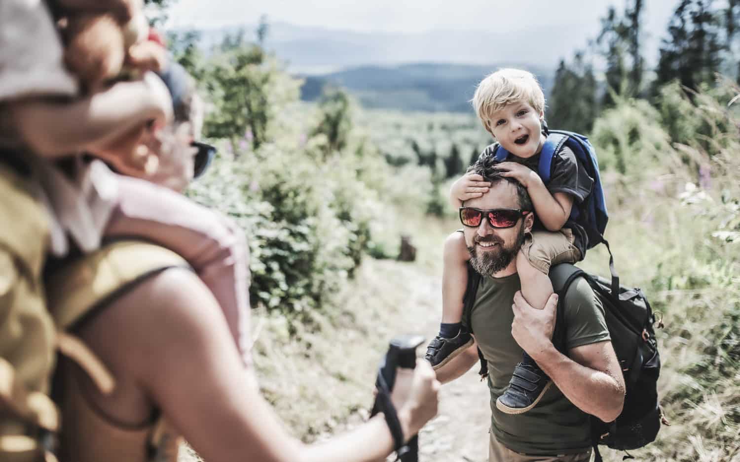 Vater trägt Kind beim Wandern auf der Schulter